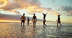 Water, friends and people on beach at sunset for holiday, vacation and weekend together. Nature, travel and back of men and women in ocean, sea and waves for adventure, freedom and relaxing outdoors