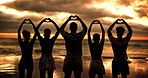 Beach, sunset and friends with heart sign for love, solidarity and bonding together on summer holiday. Group of people, connection and relationship with hands for shape, freedom and travel from back
