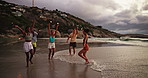 Running, happy and friends on beach at sunset for holiday, vacation and weekend together. Nature, travel and men and women by ocean, sea and waves for adventure, freedom and celebrate outdoors