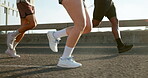 Fitness, legs and group with running on bridge for marathon training, cardio exercise and performance pace. People, runner club and sneakers in road for wellness competition, morning jog and workout