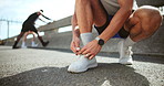 Hands, tie shoe and man with fitness, wellness and prepare with training, outdoor and warm up. Closeup, athlete and runner in city street, practice and workout with sneakers, sports and New York