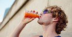 Fitness, man and drink juice in city for wellness, thirsty and healthy beverage for body care. Athlete, sunglasses and carrot extract at wall for antioxidants, vitamin A and energy boost for exercise