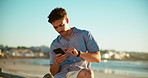 Nature, man and relax with phone at promenade for fresh air, travel freedom and holiday destination. Wind, person and smartphone at coast for checking notification, internet connection and vacation