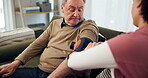 Senior care, blood pressure and caregiver in nursing home, checking and sphygmomanometer in lounge. Healthcare, nurse and rehabilitation for elderly person with inflated cuff and medical professional