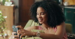 African woman, phone and relax on sofa in home, texting and smile for notification with online dating. Person, happy and smartphone on couch in living room with mobile app, chat or social network