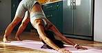 Woman, yoga and downward dog on floor, home and stretching for wellness, muscle and circulation in kitchen. Girl, pilates and balance with body movement, chakra and routine in morning at apartment