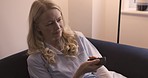 Watching tv, entertainment and streaming with a woman on her sofa in the living room to relax at home. Television, movie and lifestyle with a female enjoying an online video or channel surfing