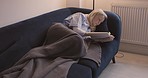 Mature woman reading, book and relax on sofa, weekend free time and relaxed in living room at home. Leisure, blanket and alone at the house, lounge and selfcare lifestyle, read books motivation.