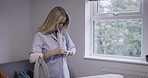 Iron, shirt and getting ready with a woman dressing in the bedroom of her home before leaving for the day. Clothes, appliance and ironing with a female in her house, putting on clothing alone