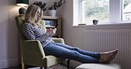 Woman, relax and phone in communication or social media, chatting or texting while sitting on chair at home. Female relaxing enjoying online conversation, sms and wifi connection on smartphone inside