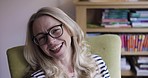Video call, talking and communication of woman sitting on a sofa and relax at home. Happy portrait, smile on her face and distance conversation by a mature laughing lady from a house living room
