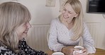Conversation, friends and middle aged women in home talking, laughing and bonding with coffee. Speaking, friendship and mature females sitting in kitchen laugh and talk together in social interaction
