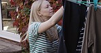 Laundry, clothes and hanging washing on clothesline by a mature woman at home in the garden. A lady doing chores, cleaning and drying wet, clean clothing on a line, outdoor in her backyard