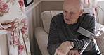 Crutch, disability and rehabilitation with a senior man talking in the living room of his retirement home. Healthcare, support and recovery with a mature patient in his house for injury healing