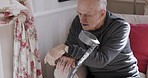 Senior man, rehabilitation and talking about health, wellness and disability with a crutch on a couch in a nursing home. Elderly patient having a conversation about physiotherapy and healthcare
