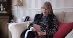 Relax, social media and senior woman on tablet reading news on internet in retirement or home in Germany. Elderly person watching movie with online subscription app while resting on living room sofa.