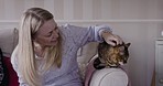 Mature woman, cat and home couch while talking and giving pet a massage for love, care and trust. Happy senior on sofa to relax and bond with calm and fur animal in living room during retirement