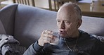 Senior man, medicine and drinking, milk for healthcare, health and wellness on the couch at home during rehabilitation and recovery. Elderly male taking chronic pills while sick at nursing home