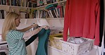 Laundry, washing and housework with a woman cleaner folding clothes after cleaning in her home. Fabric, clothing and cleaning with a female housekeeper working with fresh linen for chores in a house