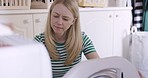 Mature woman, washing machine and doing laundry while loading clothes or fabric in front loader for cleaning at, home. Cleaner, housewife or worker doing spring cleaning for clean and fresh house