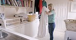 Home, laundry and woman fold fabric or fresh sheets and putting in laundry basket. Hygiene, housework and young female organizing bed linen after cleaning and washing in laundry room of house alone.