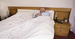 Bed, wake up and alarm with a senior man in the bedroom of his retirement home in the early morning. Sleep, rest and health with an elderly male pensioner waking up and checking his phone in a house