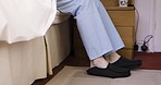 Wake up and senior man feet with morning shoes while sitting on bed in cozy home bedroom with pajamas. Old person in retirement while barefoot with warm and soft slipper for comfort
