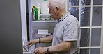 Fridge, food and home of retirement man eating grapes for snack, health and wellness nutrition. Fruit, hungry and elderly man with appetite searching and thinking of meal idea in kitchen at night.

