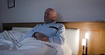 Senior man with stomach ache, pain or sickness while relaxing in the bedroom at his home. Sick, unhappy and elderly guy in retirement lying in a bed with abdomen illness, indigestion or constipation.