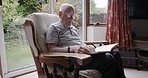 Senior man, reading book and coffee drink, relax and sofa in living room, story and novel for knowledge and language. Elderly male, glasses and read in chair, lounge and eyewear and content or calm