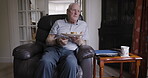 Senior man, eating and lunch sitting on home sofa with sandwich or bread on plate while hungry and alone in retirement. Old man with food on living room couch in Uk house to relax while thinking