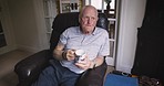 Senior man, thinking and drinking coffee in house and nursing home living room with past memory, retirement planning and ideas. Elderly, tea cup and hot drink on armchair furniture in relax apartment