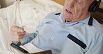 Senior man, phone and headphones while listening to music, singing and learning gospel song in bed for morning motivation and to relax in home. Old person moving hands while streaming audio online