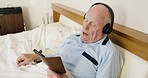 Phone, bedroom and old man listening to music for calm or peaceful relaxing while reading lyrics to a song online. Dance, headphones and elderly enjoys dancing while streaming audio, sound or radio