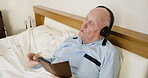 Phone, music and relax with a senior man singing while lying in a bed in the bedroom of his retirement home. Rest, morning and headphones with a mature male streaming or listening to audio in a house