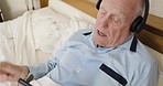 Headphones, phone and senior man relax in bedroom streaming music, radio or podcast. Retirement, mobile smartphone and elderly male from Canada listening to audio, song or sound track in house alone.