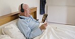 Bed, learning and elderly man relax with music, audiobook and podcast for speech, language and communication improvement. Headphones, e learning and senior man in bedroom for recovery and talk skills
