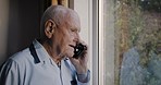 Senior man, window and phone call at window while talking about emergency, intruder and panic while upset, suspicious and worried. Old person with smartphone for communication while waiting for help