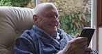Elderly man, retirement and smartphone call in armchair of living room at home with wifi network connection. Senior in bathrobe, happy cellphone communication and relax while talking online on chair 