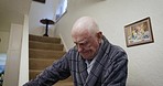 Senior man, climbing and down steps in a home, slow and careful while holding railings for balance. Retirement, frail care and elderly man having trouble walking on steps of care facility or house