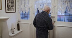 Senior man, unlocking door and to open and welcome visitor or to check locks to ensure safety and security at home. Male walking down stairs in bathrobe to front door for guest in secure UK house