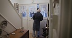 Senior man opening the house door with keys alone for a delivery at his town home in England. Unlock, pensioner and real elderly guy in retirement checking outside in the street or road in London.