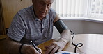 Digital, hypertension and machine of senior man for blood pressure, wellness and results. Retirement, self care and independent elderly male monitoring health with note in Australia home.

