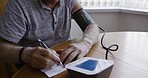 Home, blood pressure and senior man with medical kit to test, monitor and check heart rate. Cardio health, retirement and sad elderly male with hypertension writing results unhappy with diagnosis