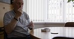 Senior man, healthcare pills and water at table for drinking glass, wellness or self care in home. Elderly male, pharma medicine or health care for pain, headache or medical drugs in morning at house