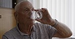 Water, pills and medicine of senior man, vitamin and drinking his morning medication in home. Elderly male in self medication, antibiotics and prescription tablets for health and wellness in house