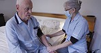 Old man with nurse, healthcare and blood pressure check with machine, retirement and nursing home. Medical care, wellness and aging with cardiovascular health woman in face mask and caregiver