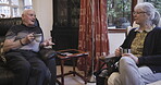 Coffee, chatting and love with a senior couple sitting in the living room of their retirement home together. Tea, conversation or bonding with a mature man and woman talking in the lounge of a house