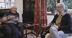 Tea, talking and love with a senior couple sitting in the living room of their retirement home together. Coffee, conversation or bonding with a mature man and woman chatting in the lounge of a house