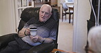 Senior man, coffee and rehab on sofa in conversation, discussion or consultation at home with caregiver. Elderly male talking about rehabilitation, progress or health to woman counselor or nurse